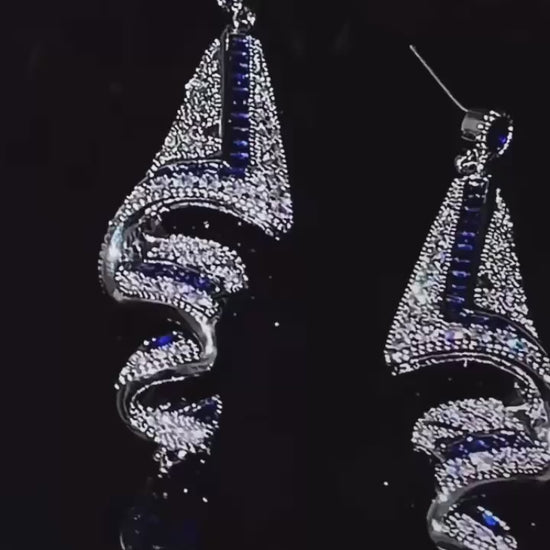 Shine with unmatched elegance wearing these stunning luxury earrings. Their geometric silver design, adorned with blue sapphire-like stones and dazzling crystals, creates a unique and sophisticated piece. Perfect for gala events, weddings, or any special occasion where you want to stand out with an exclusive and refined accessory