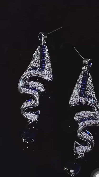 Shine with unmatched elegance wearing these stunning luxury earrings. Their geometric silver design, adorned with blue sapphire-like stones and dazzling crystals, creates a unique and sophisticated piece. Perfect for gala events, weddings, or any special occasion where you want to stand out with an exclusive and refined accessory